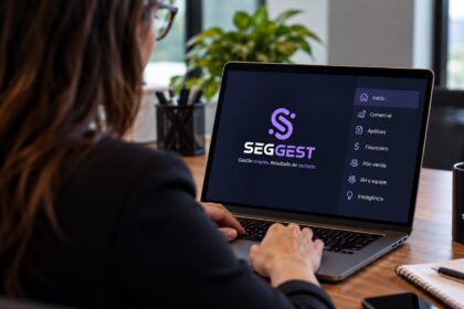 Pessoa usa notebook com a tela do sistema Seggest aberta, mostrando o menu com opções de Início, Comercial, Apólices, Financeiro, Pós-venda, RH e Inteligência